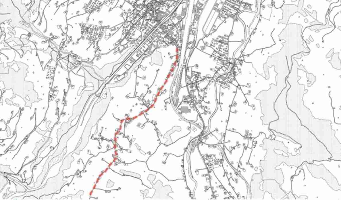 Kartenausschnitt von Frutigen mit Gemeindestrassen: Eine rot gestrichelt markierte Strecke verläuft von Norden nach Süden durch das Gebiet, umgeben von schwarz-weiss dargestelltem Strassennetz, Gebäudegrundrissen, Bahnlinie und topografischen Geländestrukturen.